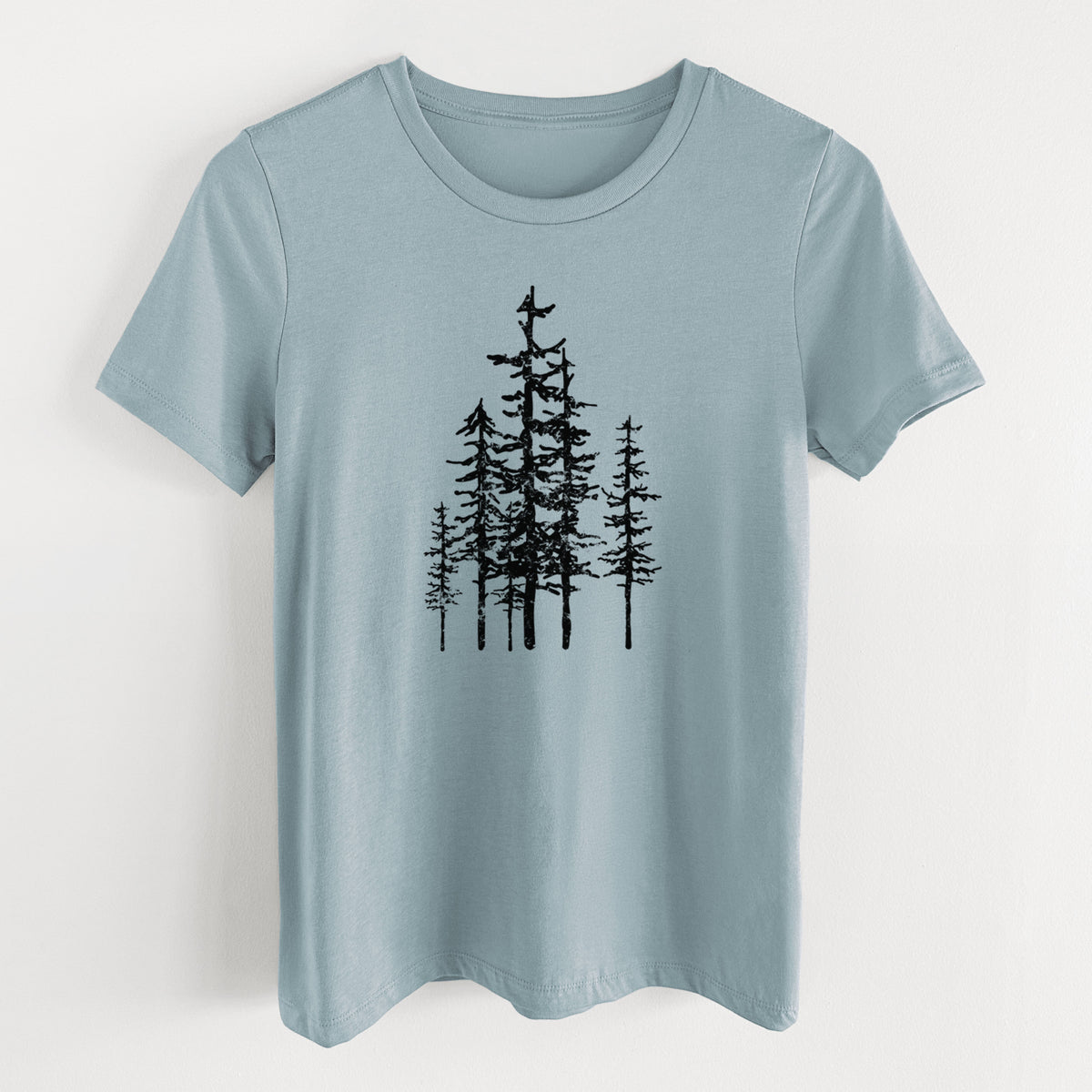 Vintage denim women's relaxed fit cotton t-shirt laid flat, printed with a black ink illustration of a cluster of evergreen trees of varying heights.