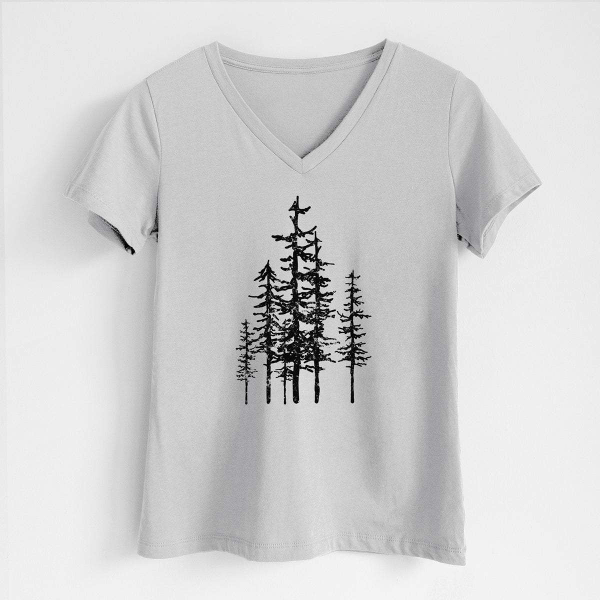 Lunar grey women's relaxed fit cotton V-neck t-shirt laid flat, printed with a black ink illustration of a cluster of evergreen trees of varying heights.