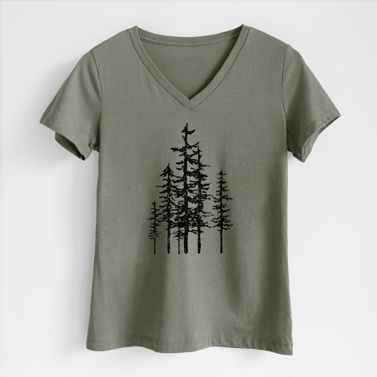 Military green women's relaxed fit cotton V-neck t-shirt laid flat, printed with a black ink illustration of a cluster of evergreen trees of varying heights.