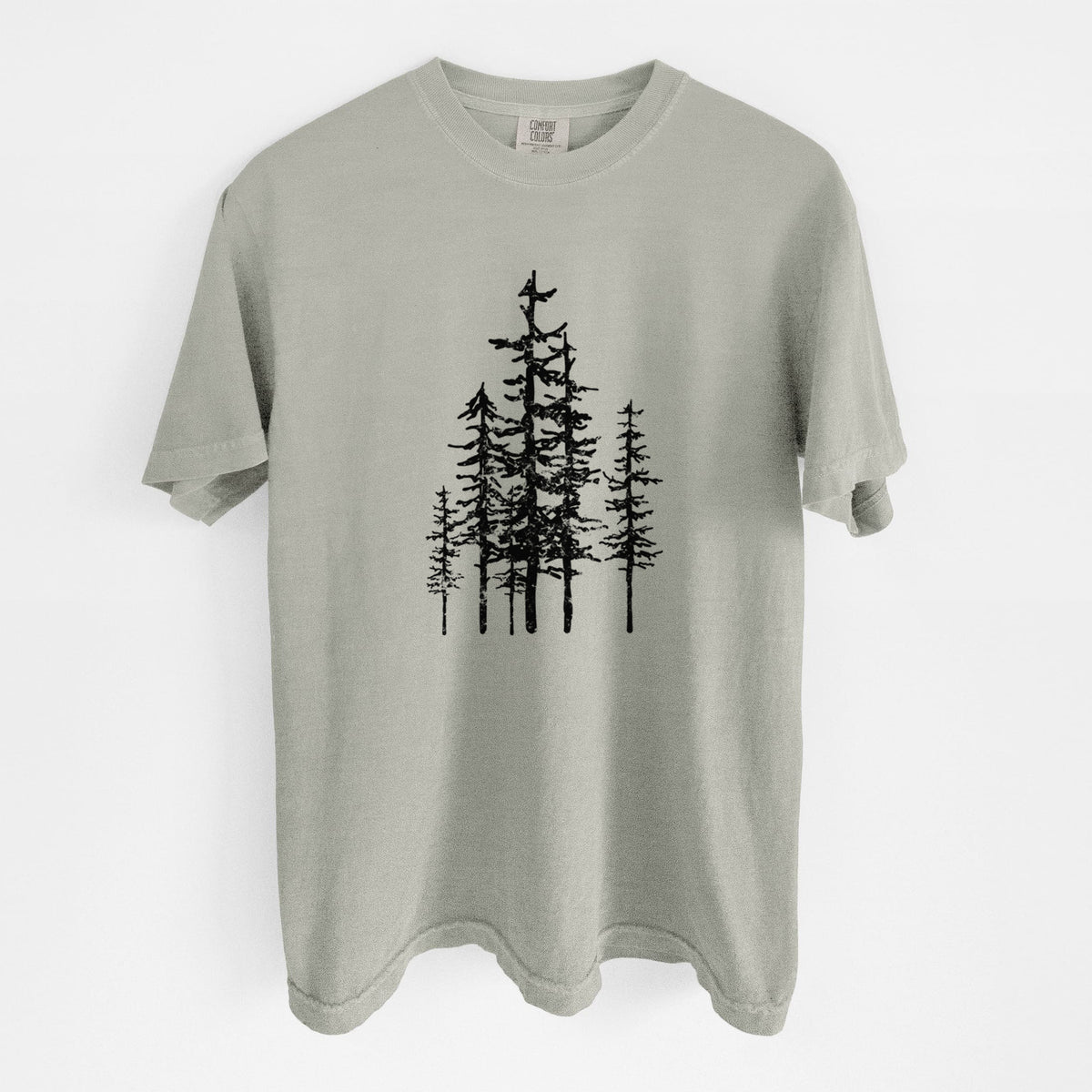Sandstone beige Comfort Colors t-shirt laid flat, printed with a black ink illustration of a cluster of evergreen trees of varying heights.