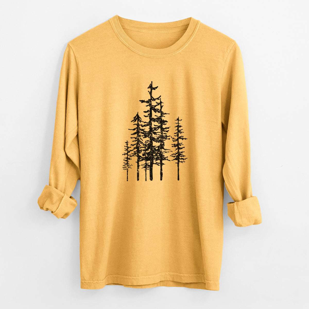 Golden wheat yellow Comfort Colors long sleeve shirt laid flat with the cuffs rolled, printed with a black ink illustration of a cluster of evergreen trees of varying heights.
