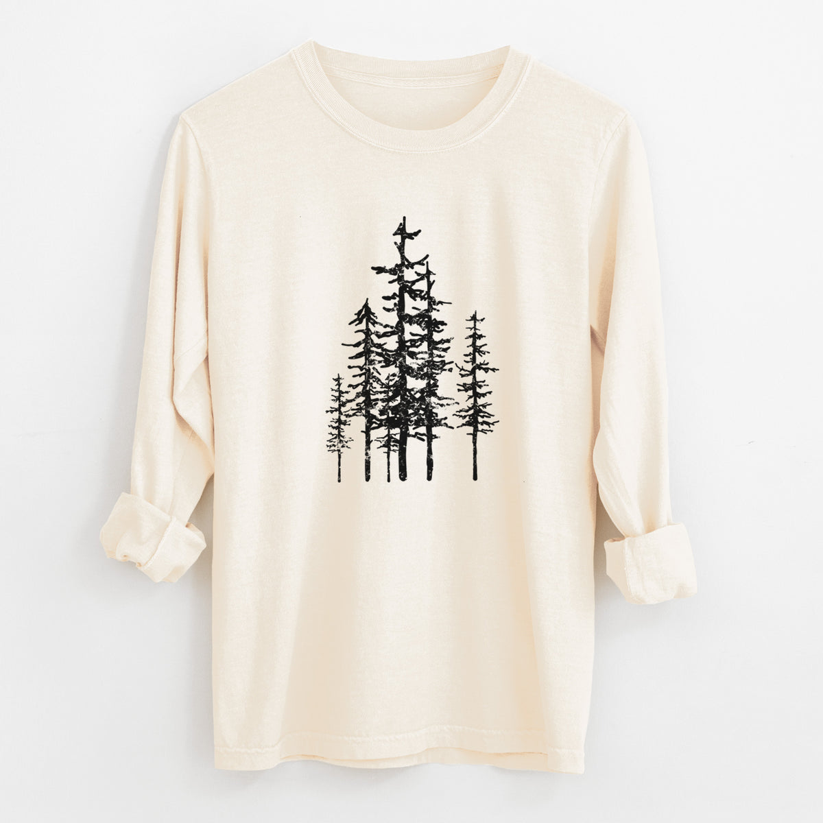 Ivory Comfort Colors long sleeve shirt laid flat with the cuffs rolled, printed with a black ink illustration of a cluster of evergreen trees of varying heights.