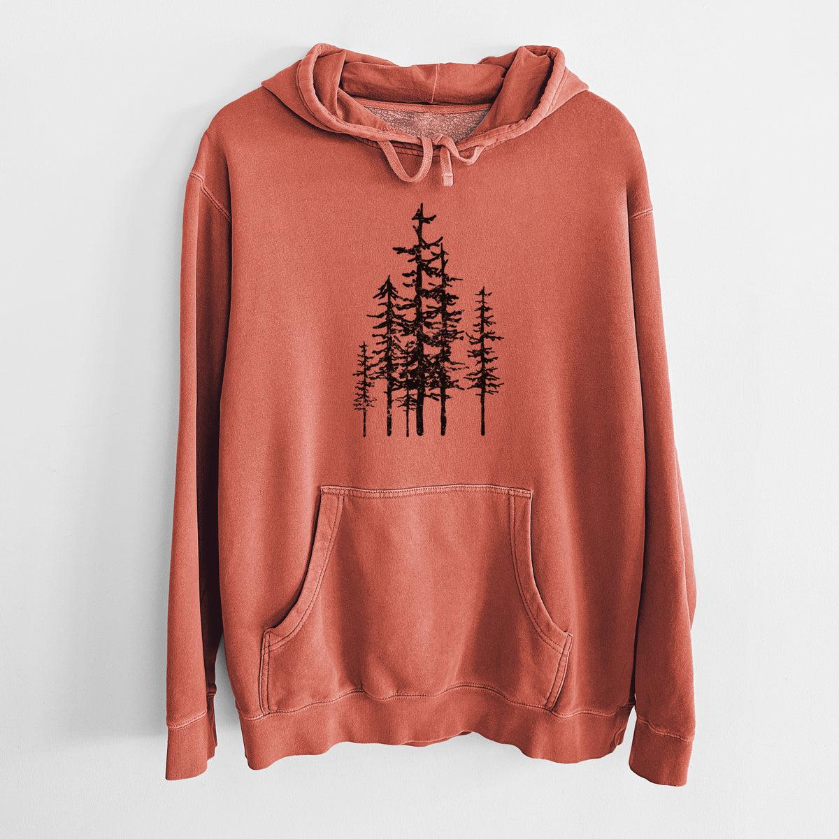 Amber orange pigment dyed hoodie laid flat, printed with a black ink illustration of a cluster of evergreen trees of varying heights.