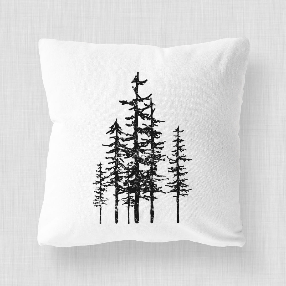 White pillow cover printed with a black ink illustration of a cluster of evergreen trees of varying heights.