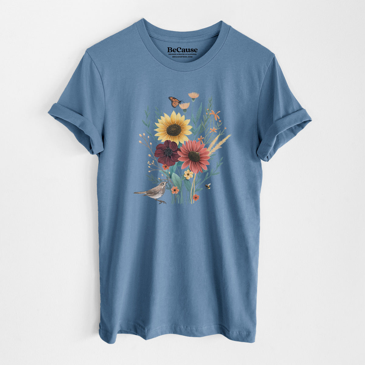 Steel blue lightweight cotton t-shirt laid flat, printed with a full-color bouquet of sunflowers, red flowers and wildflowers with butterflies and a small bird.