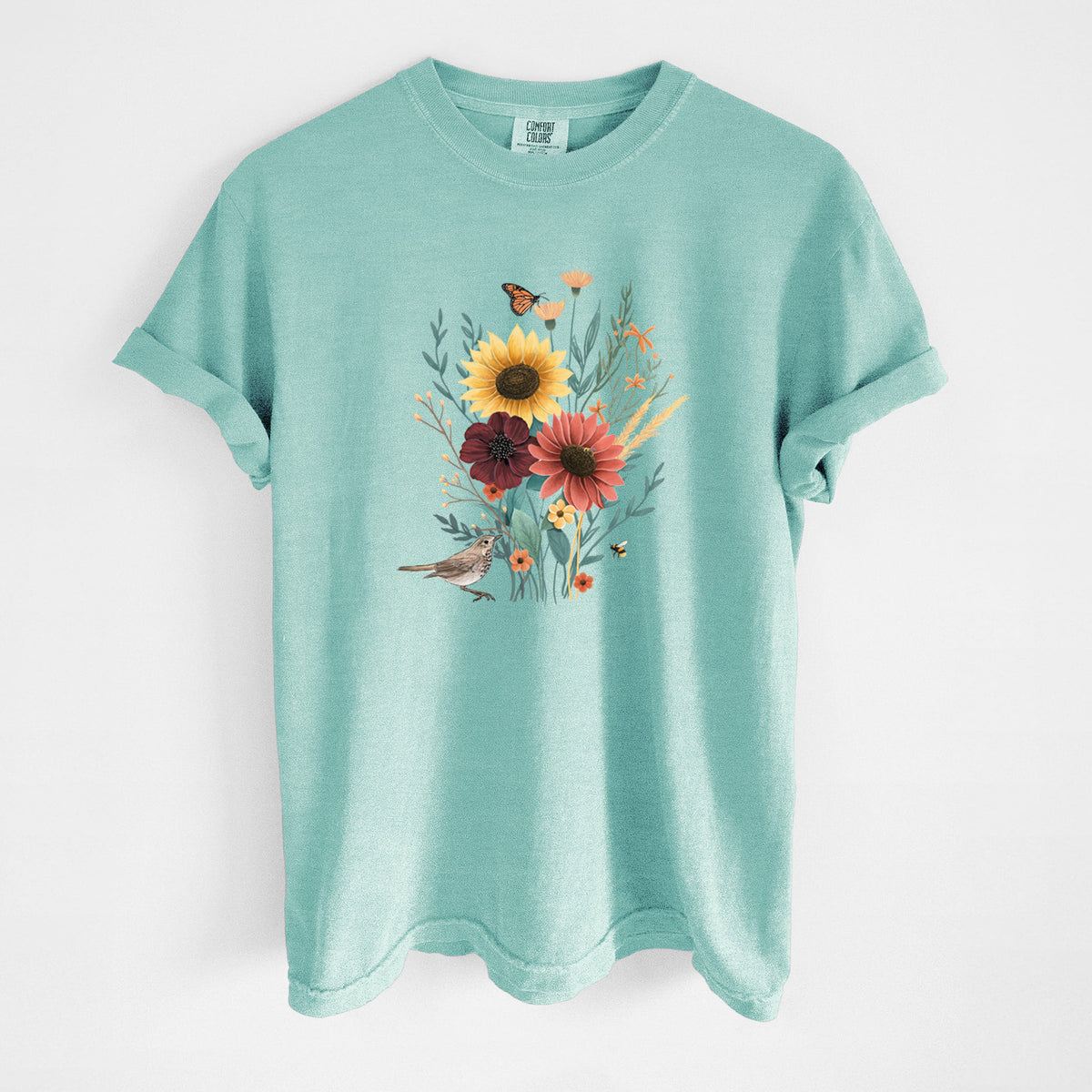Chalky mint Comfort Colors t-shirt laid flat, printed with a full-color bouquet of sunflowers, red flowers and wildflowers with butterflies and a small bird.