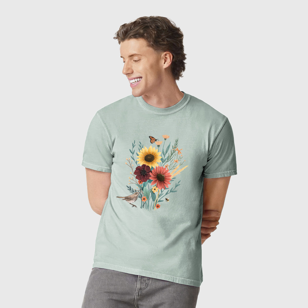 Man wearing a Comfort Colors t-shirt printed with a full-color bouquet of sunflowers, red flowers and wildflowers with butterflies and a small bird.