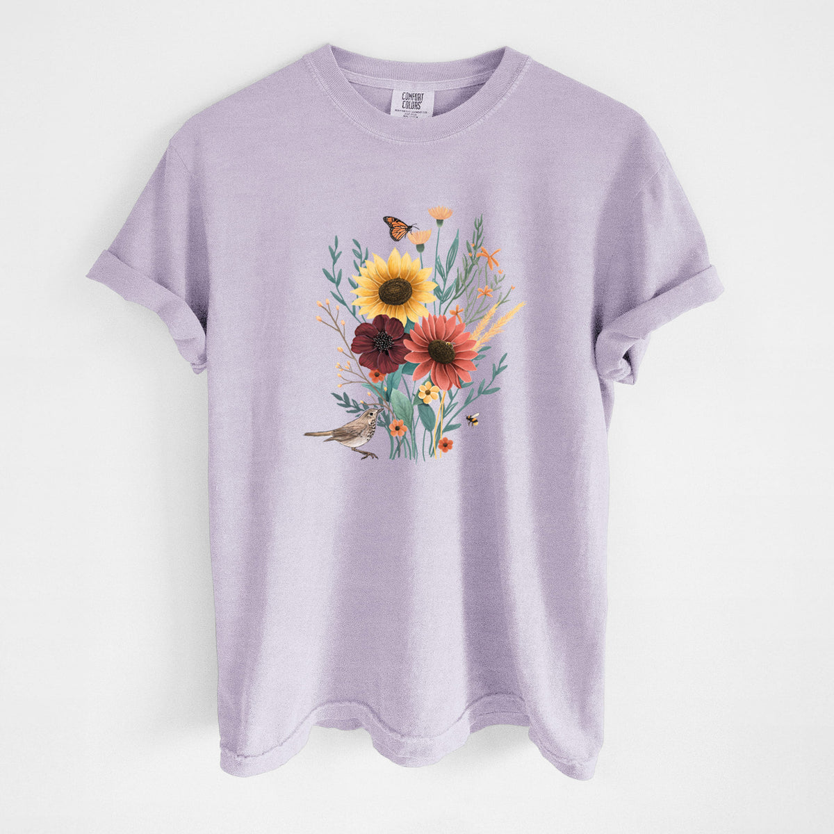 Orchid purple Comfort Colors t-shirt laid flat, printed with a full-color bouquet of sunflowers, red flowers and wildflowers with butterflies and a small bird.