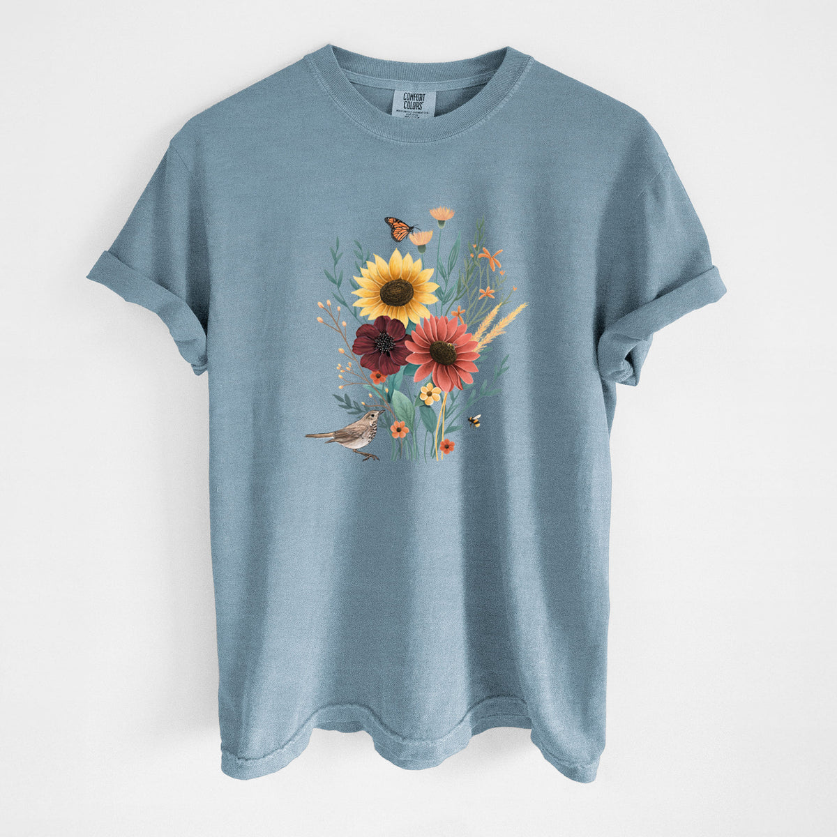 Steel blue Comfort Colors t-shirt laid flat, printed with a full-color bouquet of sunflowers, red flowers and wildflowers with butterflies and a small bird.