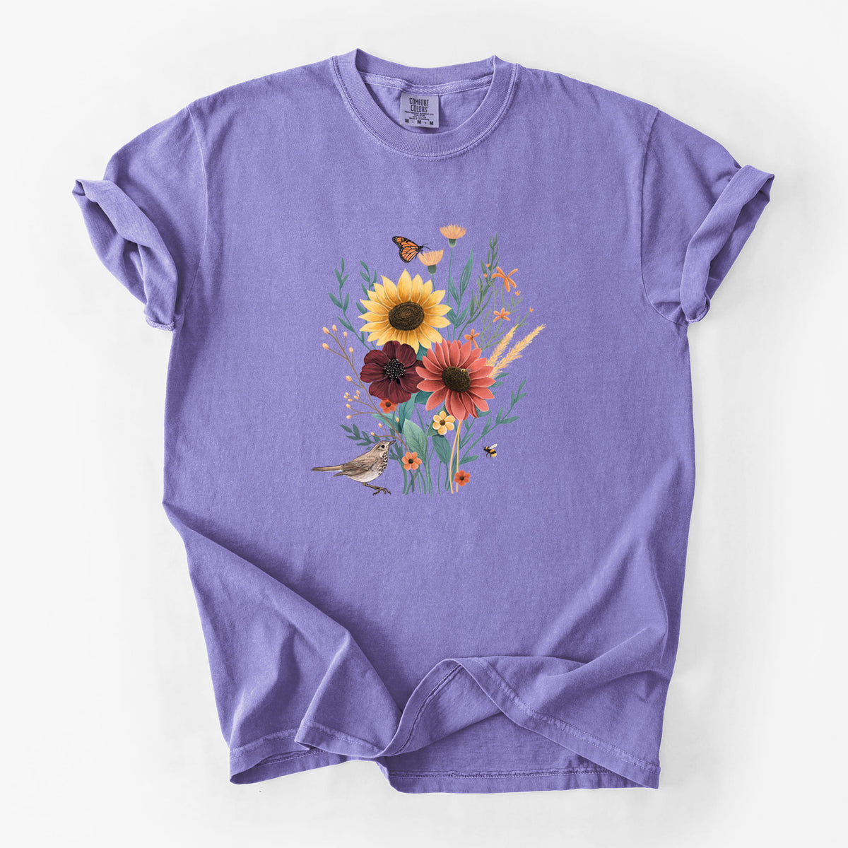 Violet purple Comfort Colors t-shirt laid flat, printed with a full-color bouquet of sunflowers, red flowers and wildflowers with butterflies and a small bird.