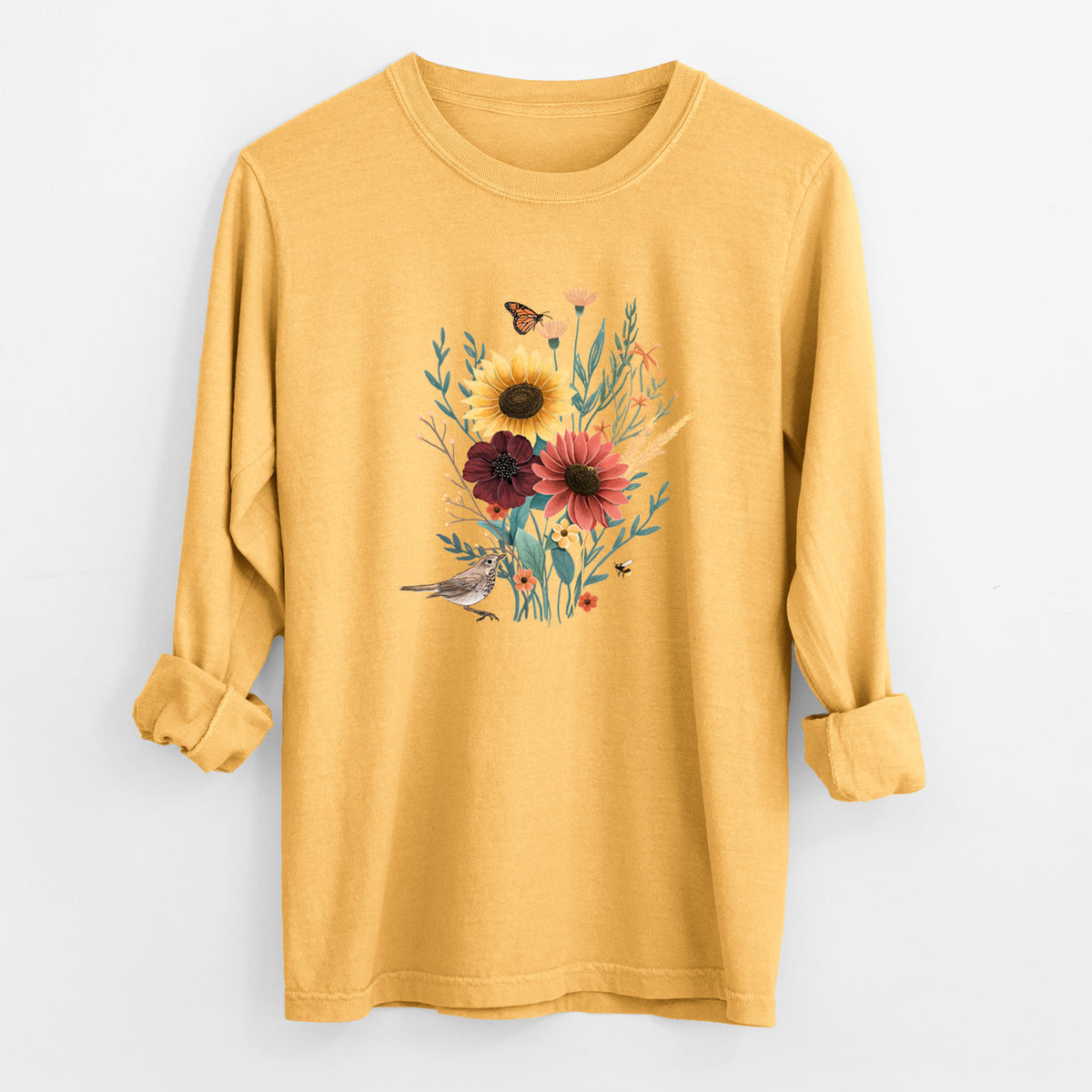 Golden wheat yellow Comfort Colors long sleeve shirt laid flat with the cuffs rolled, printed with a full-color bouquet of sunflowers, red flowers and wildflowers with butterflies and a small bird.
