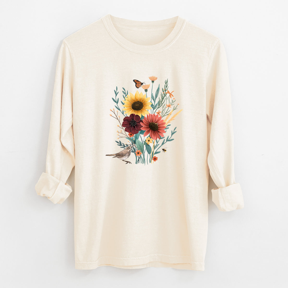 Ivory Comfort Colors long sleeve shirt laid flat with the cuffs rolled, printed with a full-color bouquet of sunflowers, red flowers and wildflowers with butterflies and a small bird.