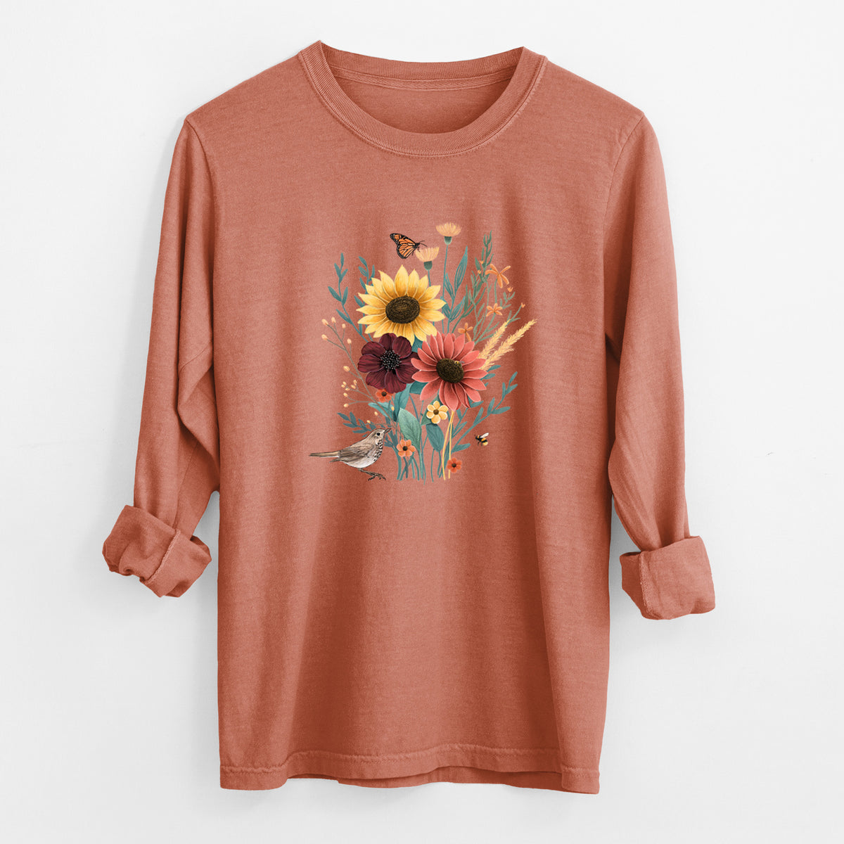 Yam burnt orange Comfort Colors long sleeve shirt laid flat with the cuffs rolled, printed with a full-color bouquet of sunflowers, red flowers and wildflowers with butterflies and a small bird.