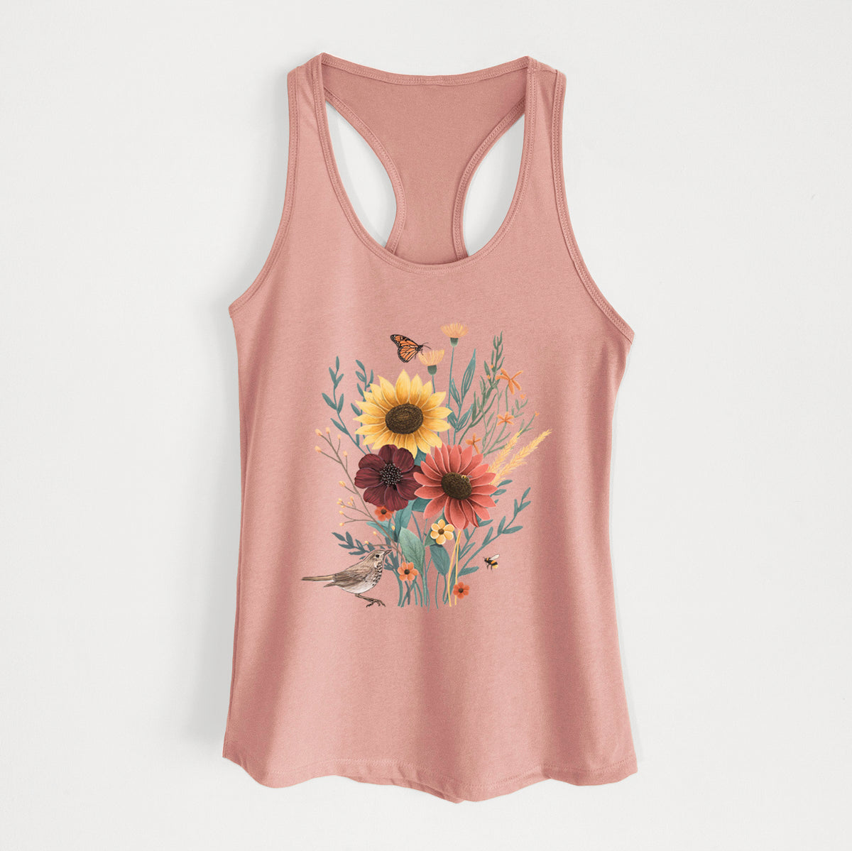 Desert pink women's racerback tank top laid flat, printed with a full-color bouquet of sunflowers, red flowers and wildflowers with butterflies and a small bird.