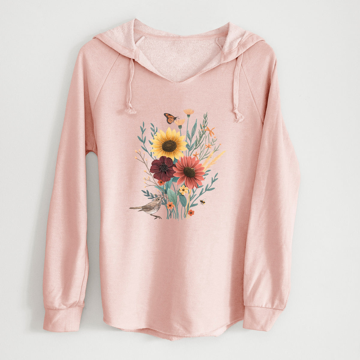 Blush pink women's Cali Wave hooded sweatshirt laid flat, printed with a full-color bouquet of sunflowers, red flowers and wildflowers with butterflies and a small bird.