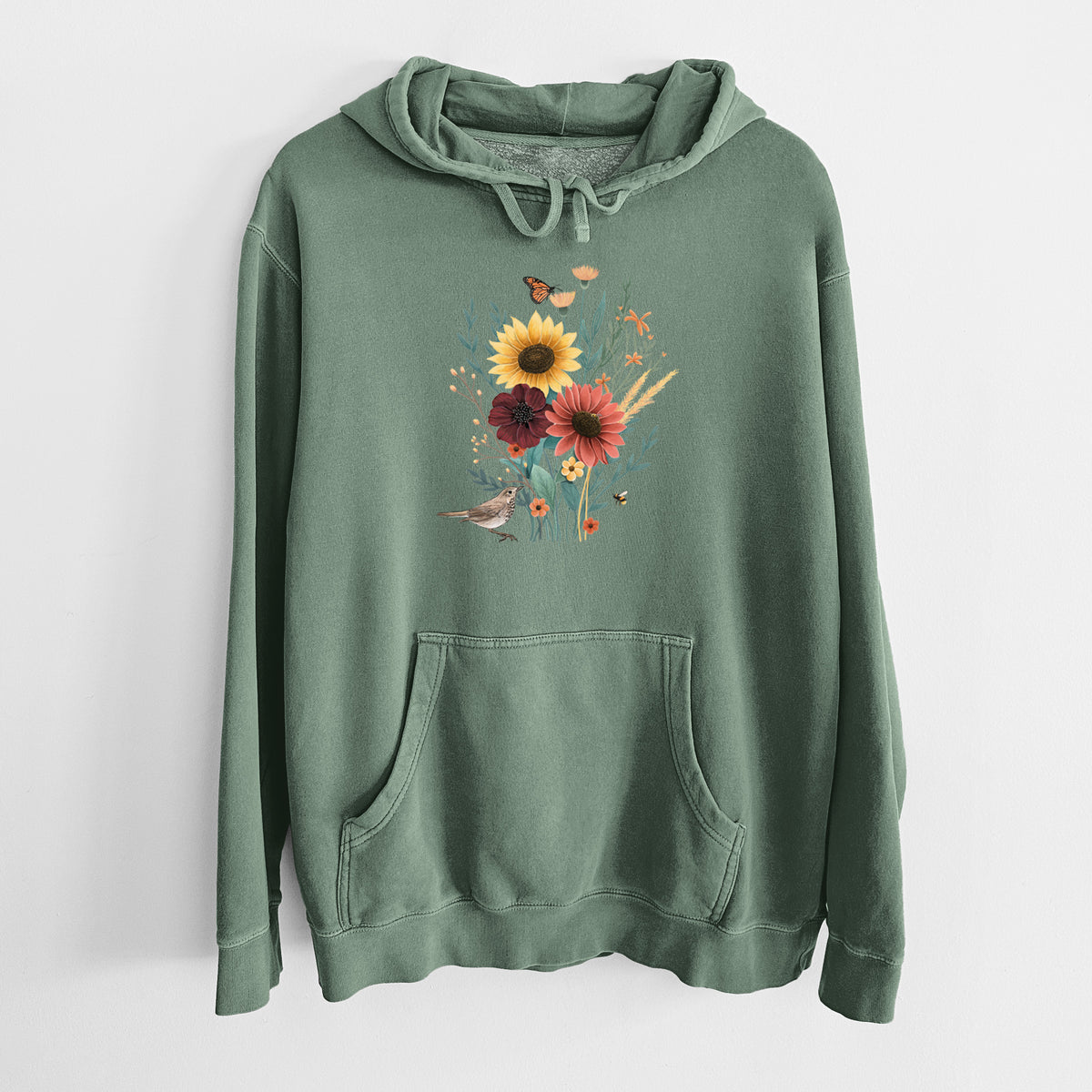 Alpine green pigment dyed hoodie laid flat, printed with a full-color bouquet of sunflowers, red flowers and wildflowers with butterflies and a small bird.