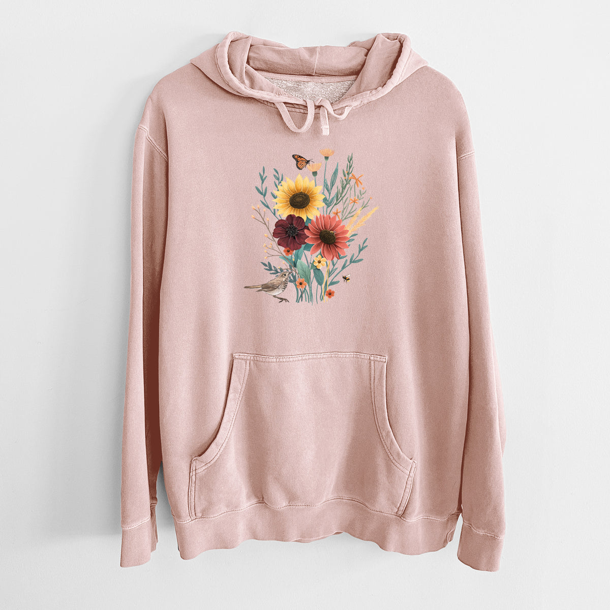 Dusty pink pigment dyed hoodie laid flat, printed with a full-color bouquet of sunflowers, red flowers and wildflowers with butterflies and a small bird.