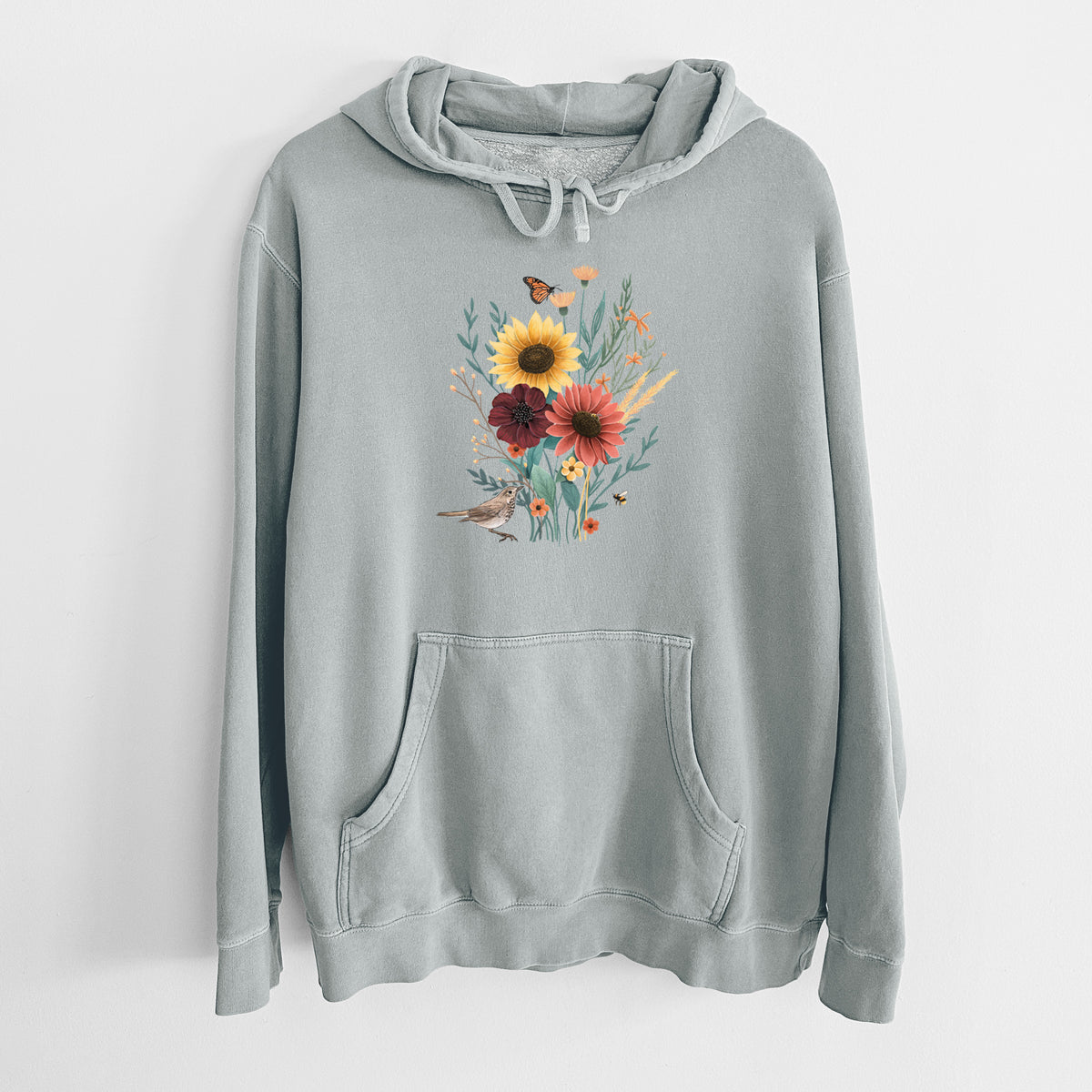Sage green pigment dyed hoodie laid flat, printed with a full-color bouquet of sunflowers, red flowers and wildflowers with butterflies and a small bird.