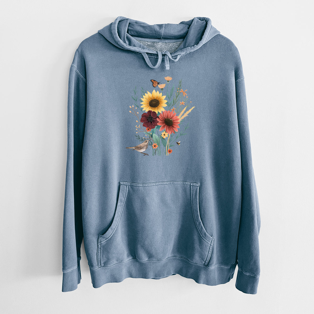 Slate blue pigment dyed hoodie laid flat, printed with a full-color bouquet of sunflowers, red flowers and wildflowers with butterflies and a small bird.