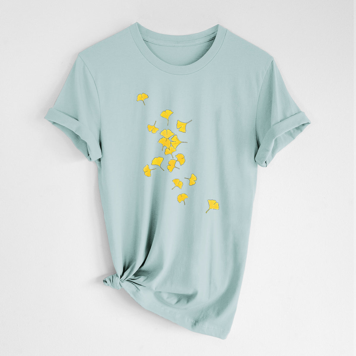 Dusty blue lightweight cotton t-shirt laid flat with the sleeves rolled, printed with a scatter of bright yellow fan-shaped ginkgo leaves falling.