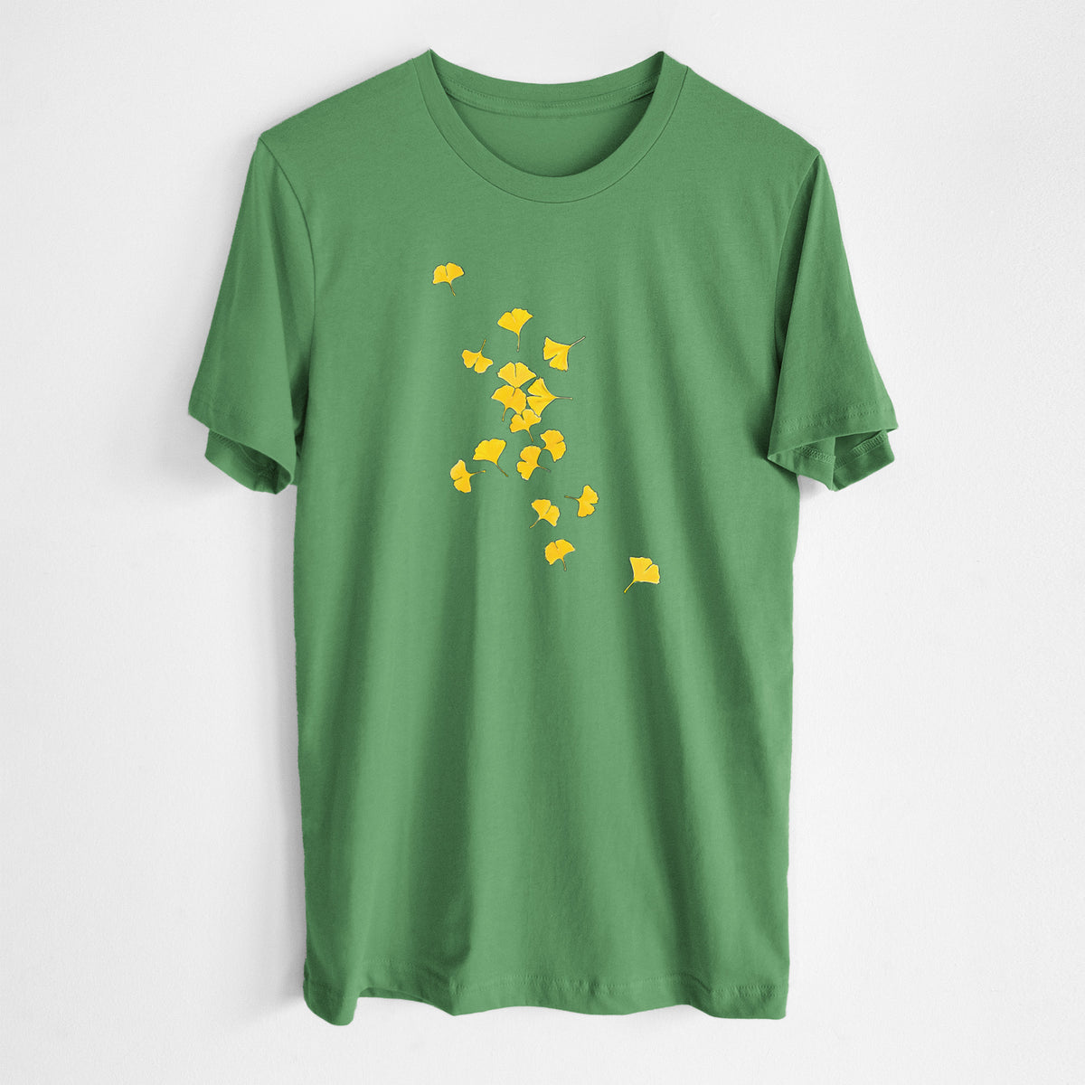 Leaf green lightweight cotton t-shirt laid flat, printed with a scatter of bright yellow fan-shaped ginkgo leaves falling.