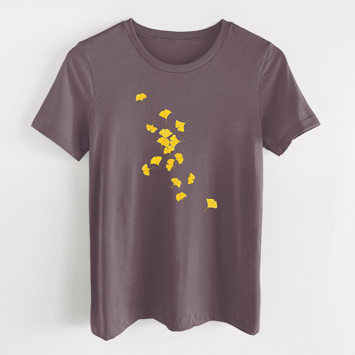 Purple storm women's relaxed fit cotton t-shirt laid flat, printed with a scatter of bright yellow fan-shaped ginkgo leaves falling.