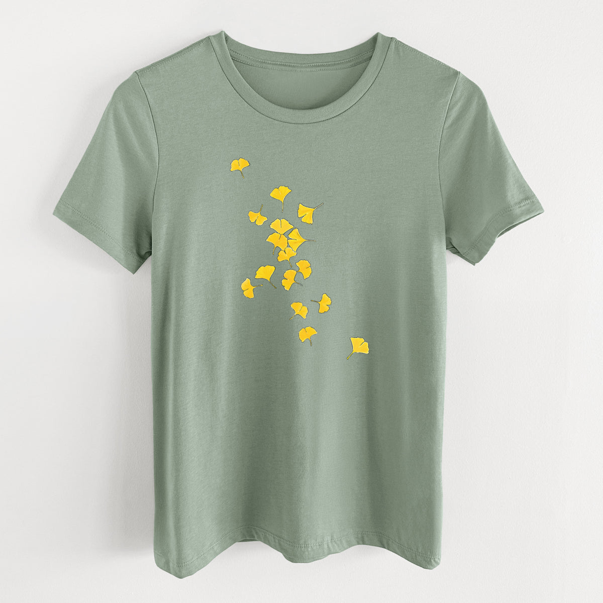 Sage green women's relaxed fit cotton t-shirt laid flat, printed with a scatter of bright yellow fan-shaped ginkgo leaves falling.
