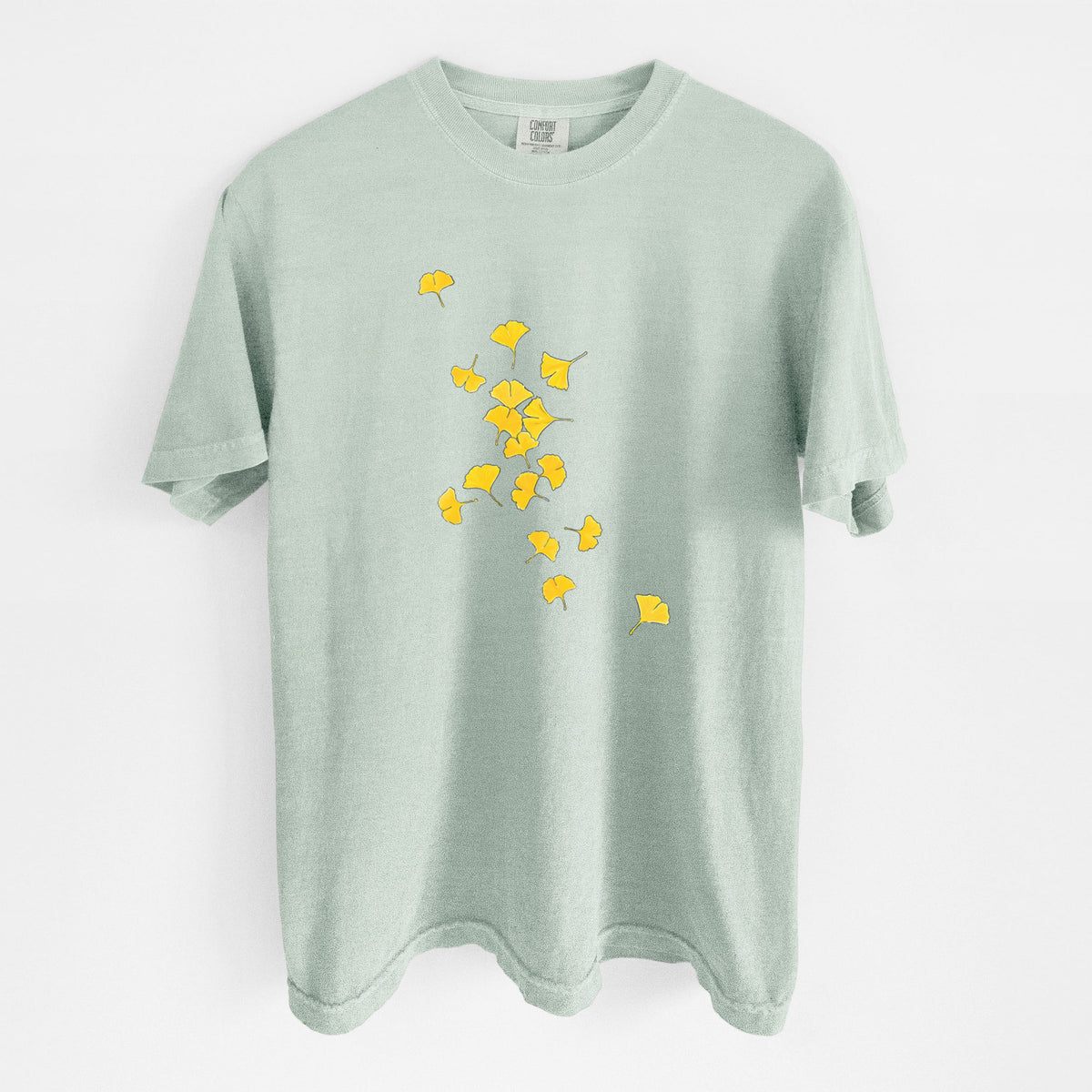 Bay green Comfort Colors t-shirt laid flat, printed with a scatter of bright yellow fan-shaped ginkgo leaves falling.