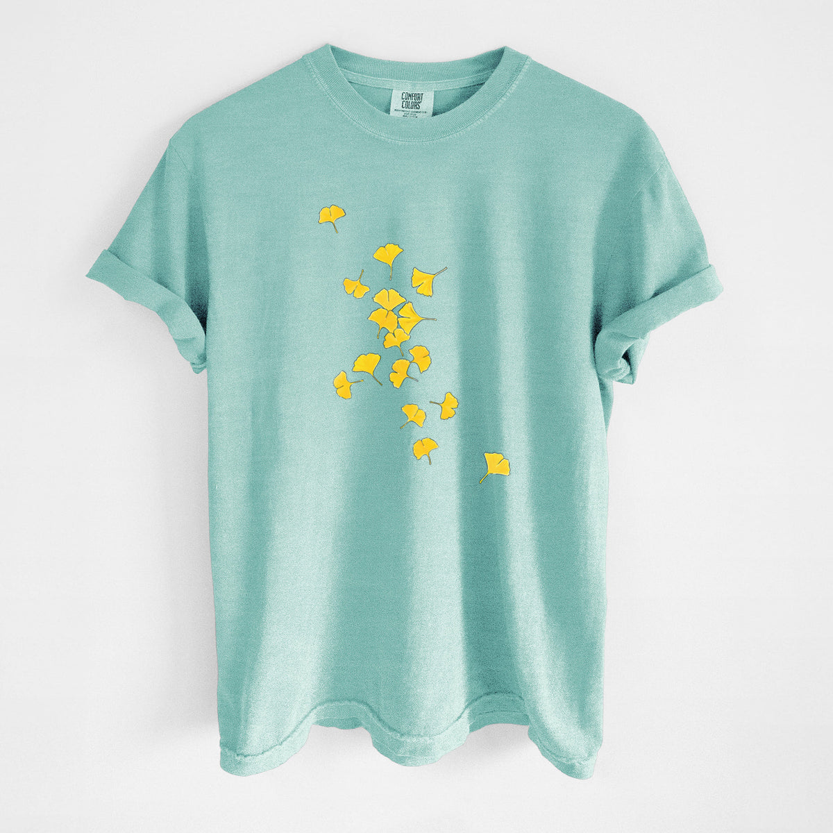 Chalky mint Comfort Colors t-shirt laid flat, printed with a scatter of bright yellow fan-shaped ginkgo leaves falling.