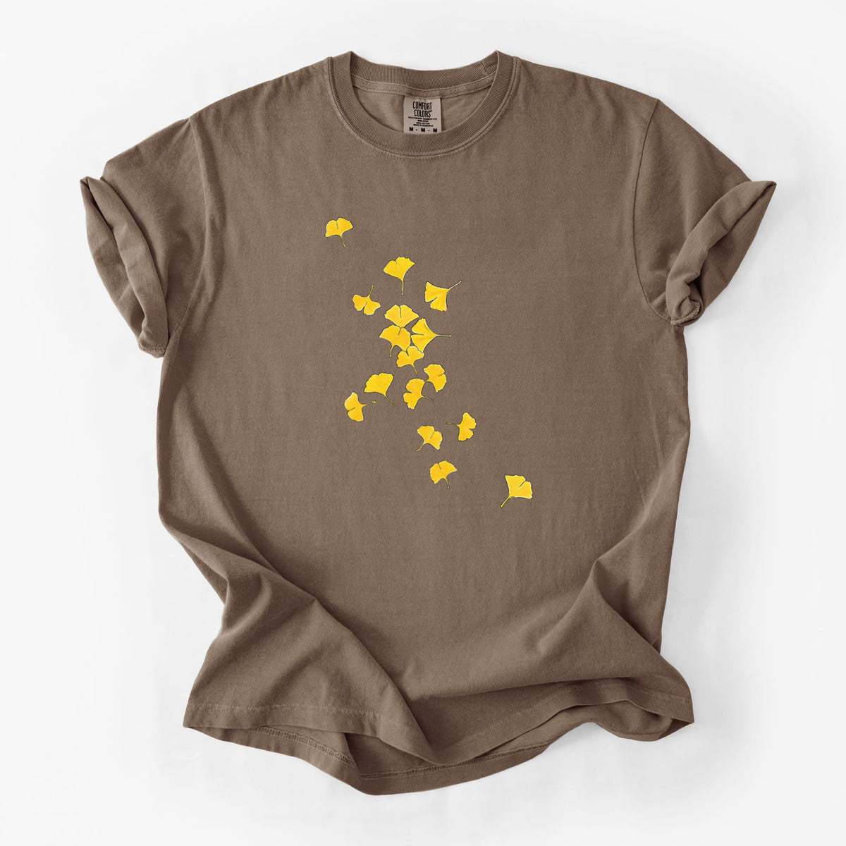 Espresso brown Comfort Colors t-shirt laid flat, printed with a scatter of bright yellow fan-shaped ginkgo leaves falling.