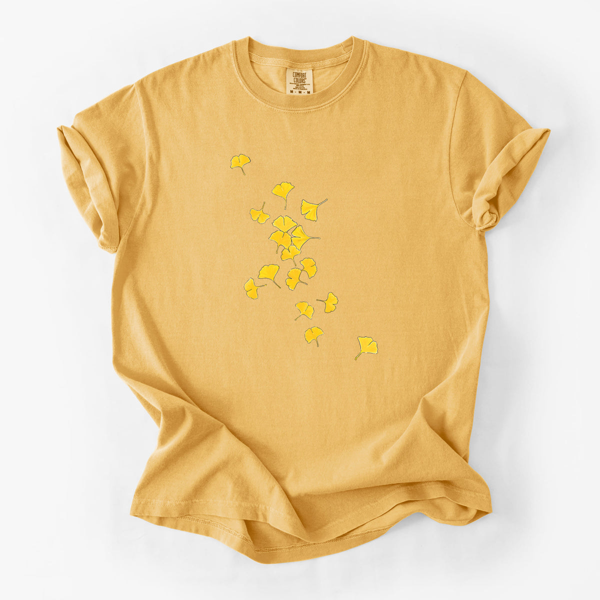 Golden wheat yellow Comfort Colors t-shirt laid flat, printed with a scatter of bright yellow fan-shaped ginkgo leaves falling.