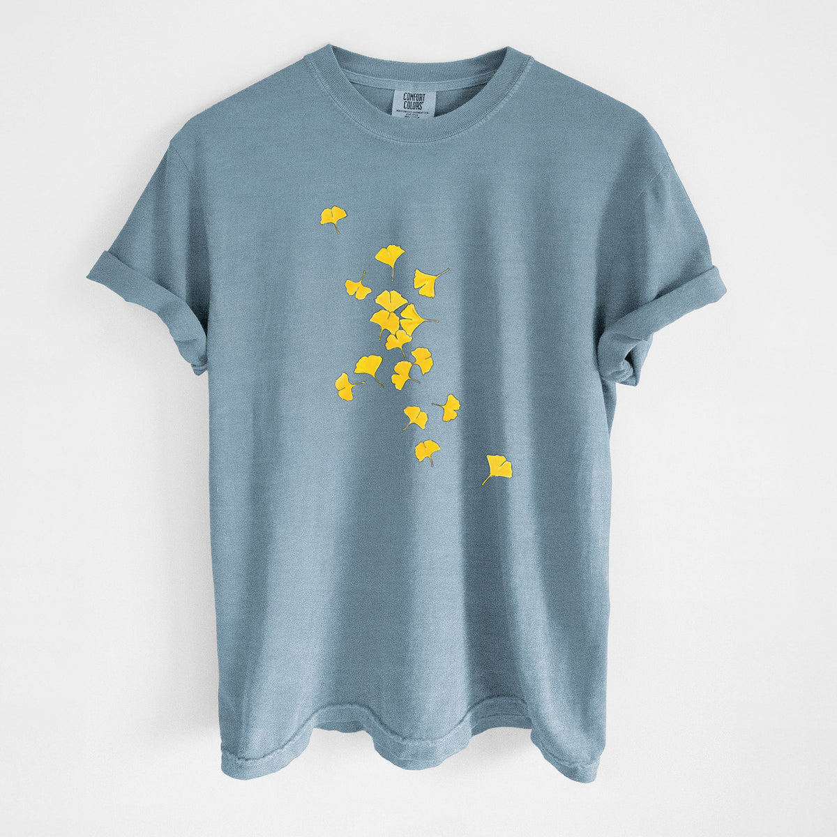 Steel blue Comfort Colors t-shirt laid flat, printed with a scatter of bright yellow fan-shaped ginkgo leaves falling.
