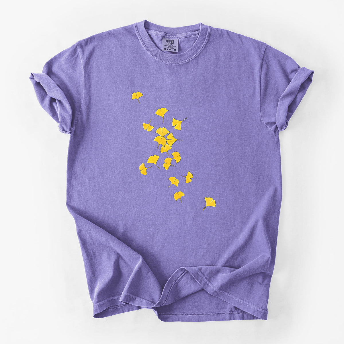 Violet purple Comfort Colors t-shirt laid flat, printed with a scatter of bright yellow fan-shaped ginkgo leaves falling.