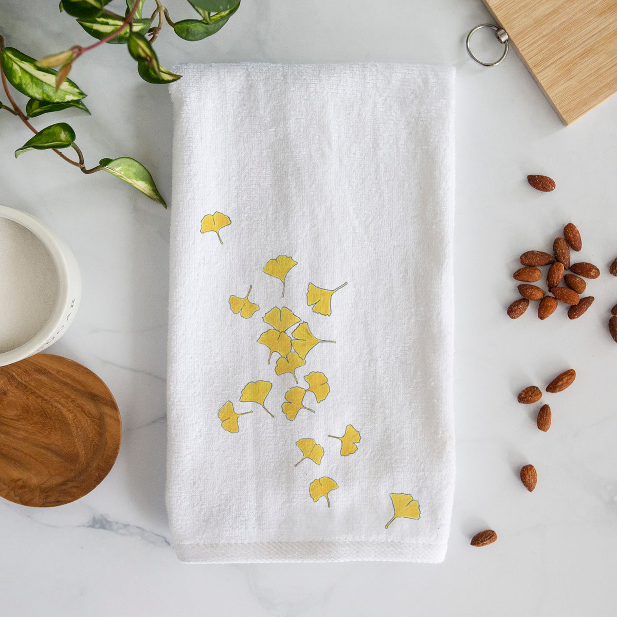 White hand towel printed with a scatter of bright yellow fan-shaped ginkgo leaves falling.