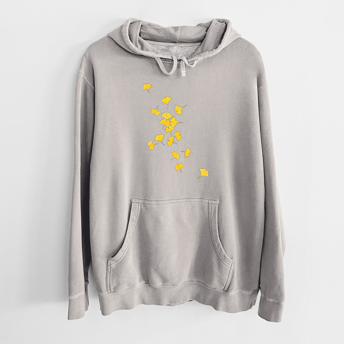 Cement grey pigment dyed hoodie laid flat, printed with a scatter of bright yellow fan-shaped ginkgo leaves falling.