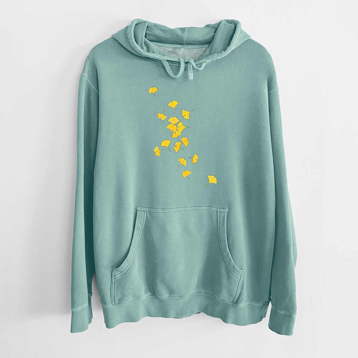 Mint green pigment dyed hoodie laid flat, printed with a scatter of bright yellow fan-shaped ginkgo leaves falling.