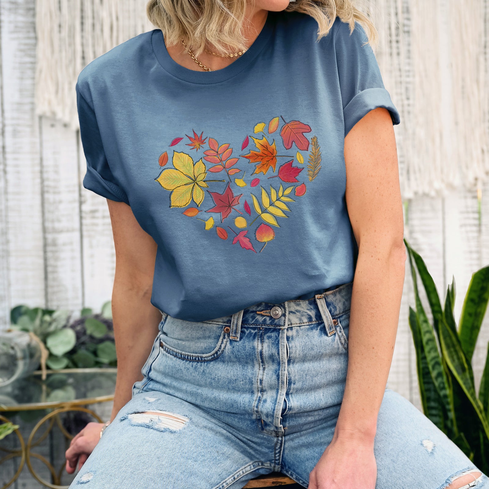 Autumn lightweight cotton t-shirt laid flat, printed with a full-color heart shape made of autumn leaves in orange, red and yellow.