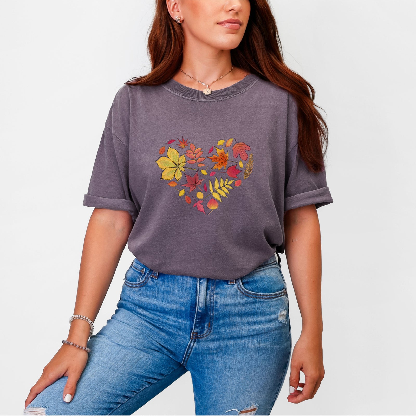 Blue jean Comfort Colors t-shirt laid flat, printed with a full-color heart shape made of autumn leaves in orange, red and yellow.
