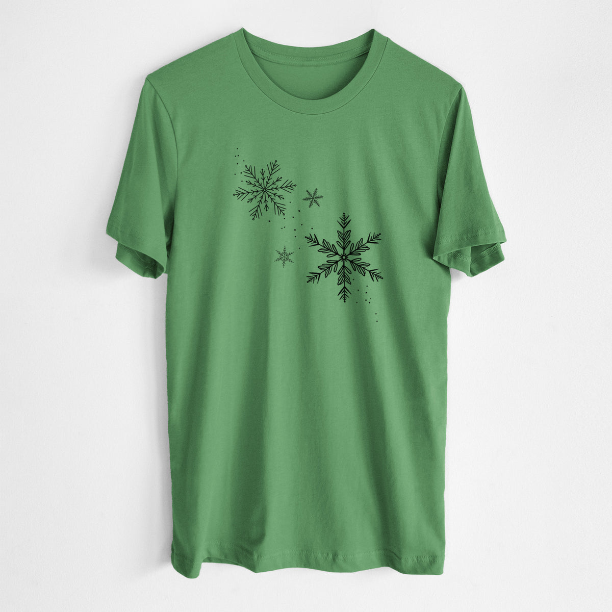 Leaf green lightweight cotton t-shirt laid flat, printed with delicate snowflakes of different sizes falling.