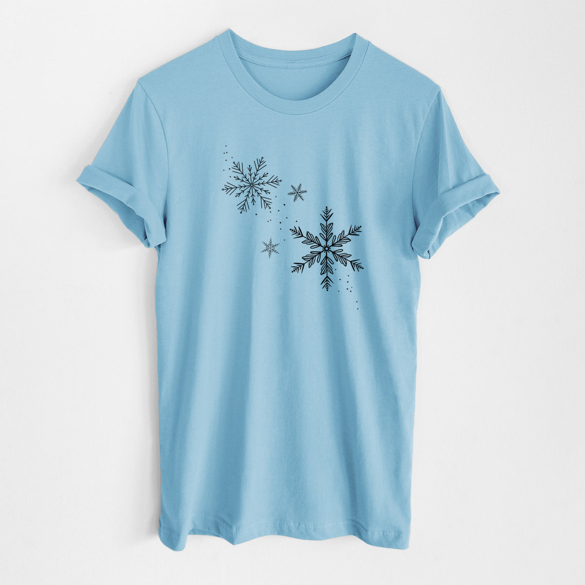 Ocean blue lightweight cotton t-shirt laid flat, printed with delicate snowflakes of different sizes falling.