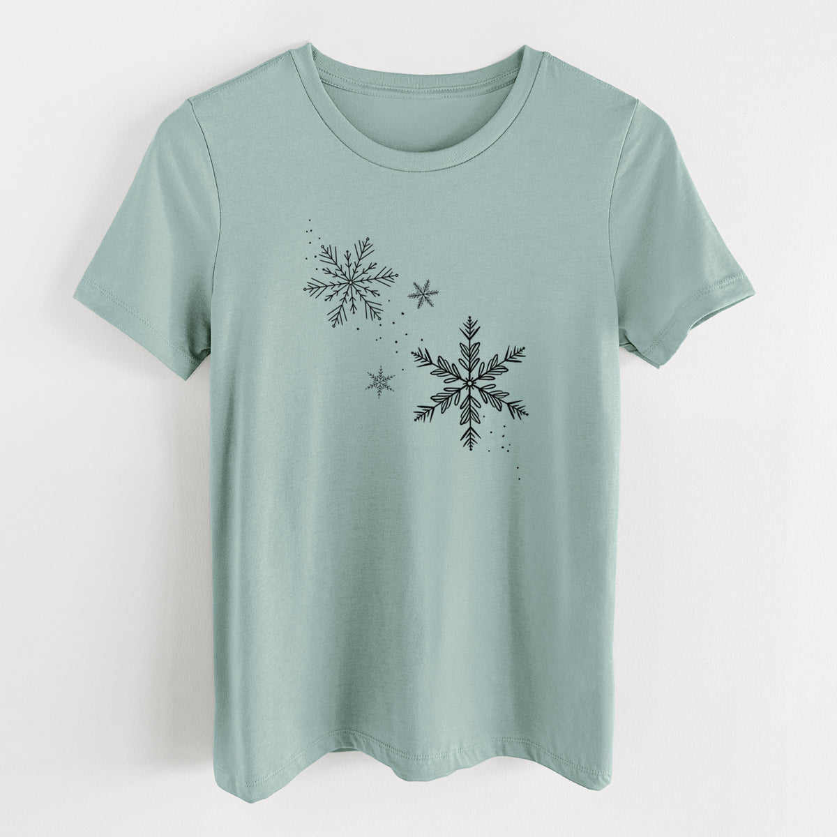 Dusty blue women's relaxed fit cotton t-shirt laid flat, printed with delicate snowflakes of different sizes falling.