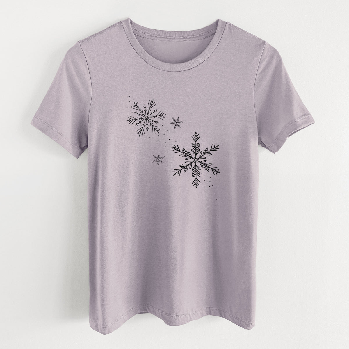 Light violet women's relaxed fit cotton t-shirt laid flat, printed with delicate snowflakes of different sizes falling.