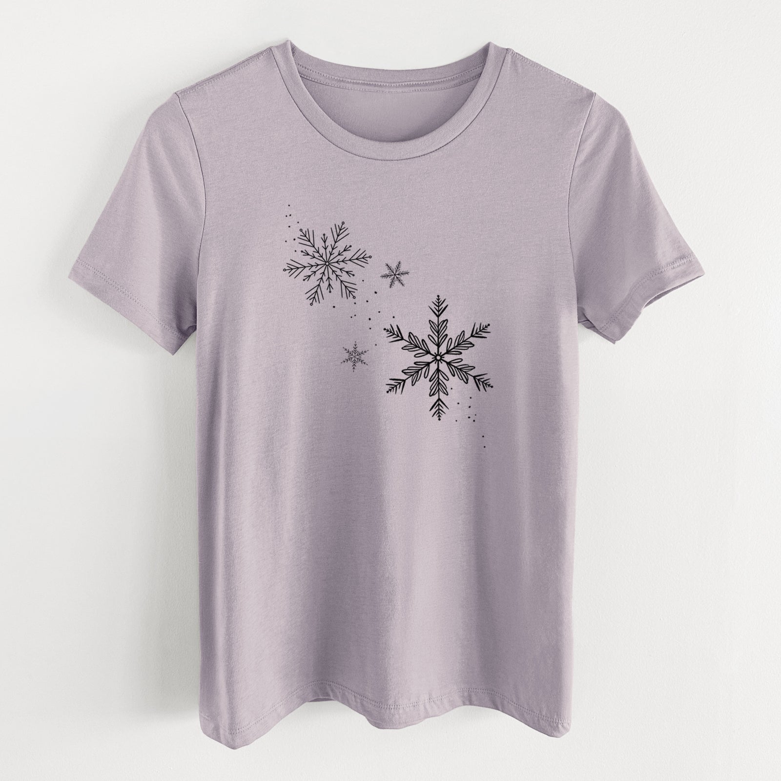 Light violet women's relaxed fit cotton t-shirt laid flat, printed with delicate snowflakes of different sizes falling.