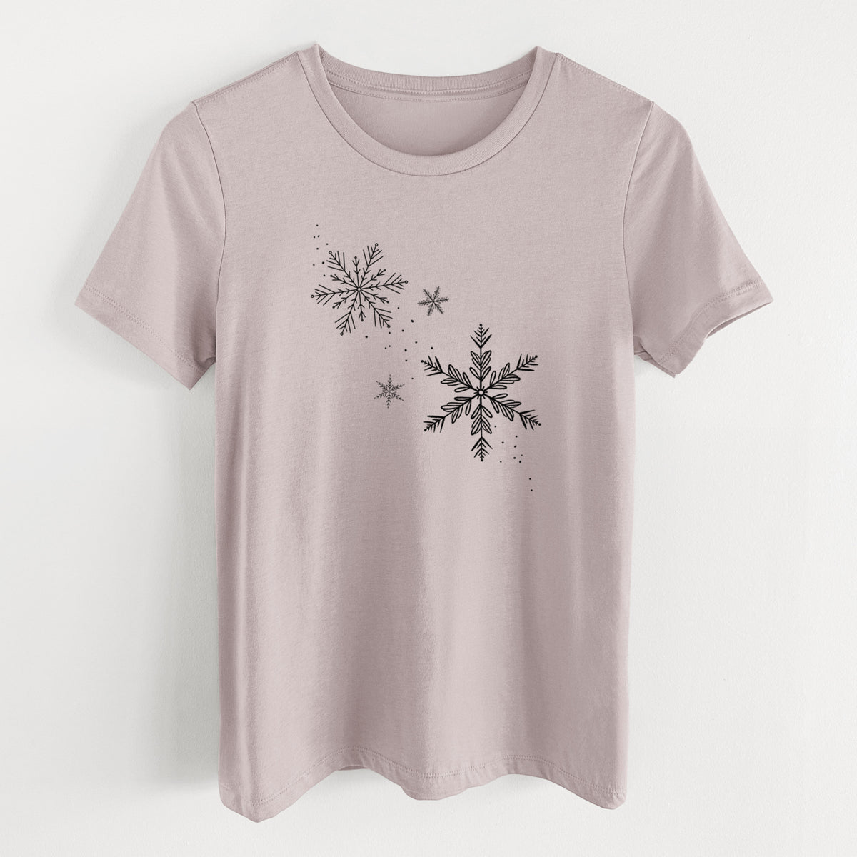 Pink gravel women's relaxed fit cotton t-shirt laid flat, printed with delicate snowflakes of different sizes falling.