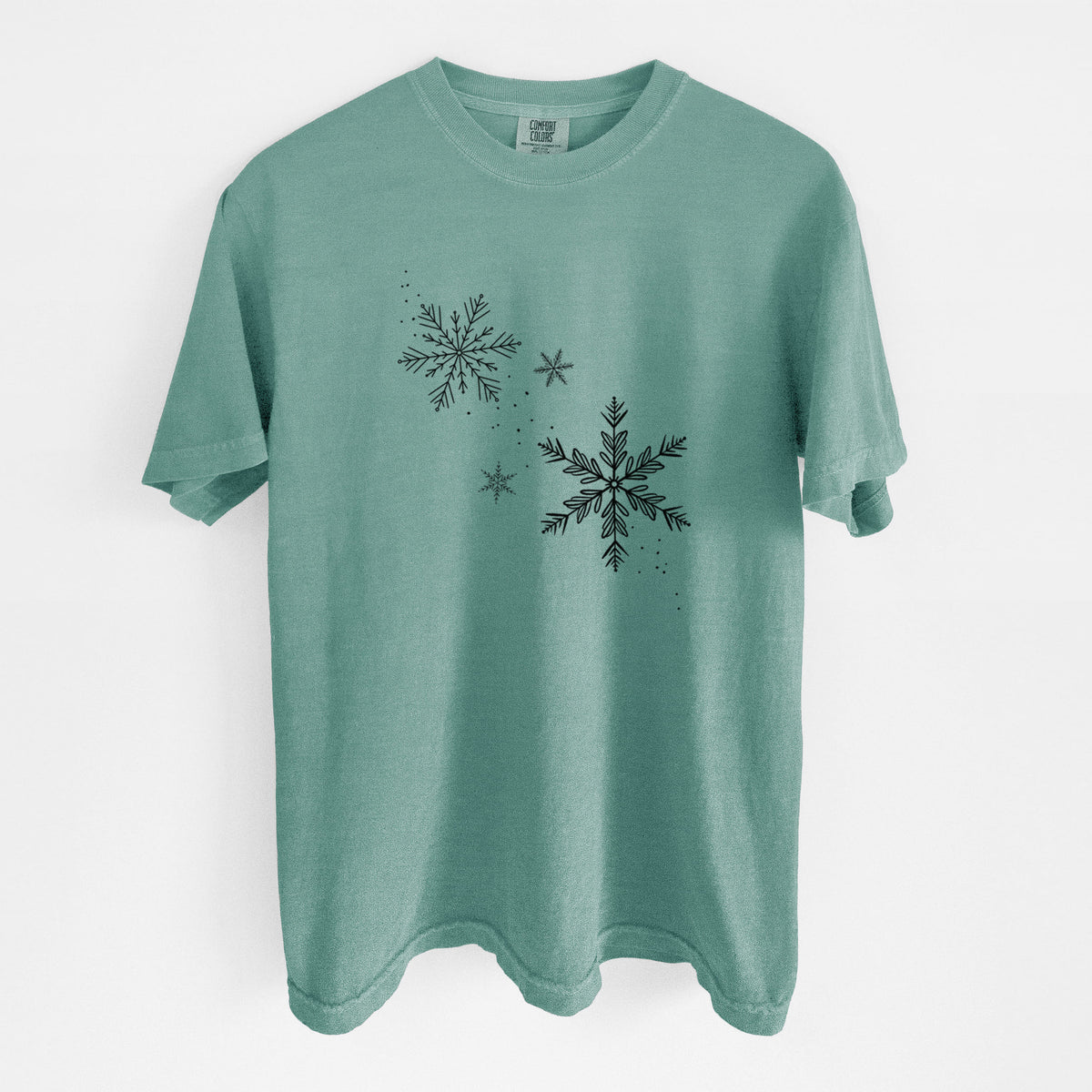 Reef green Comfort Colors t-shirt laid flat, printed with delicate snowflakes of different sizes falling.