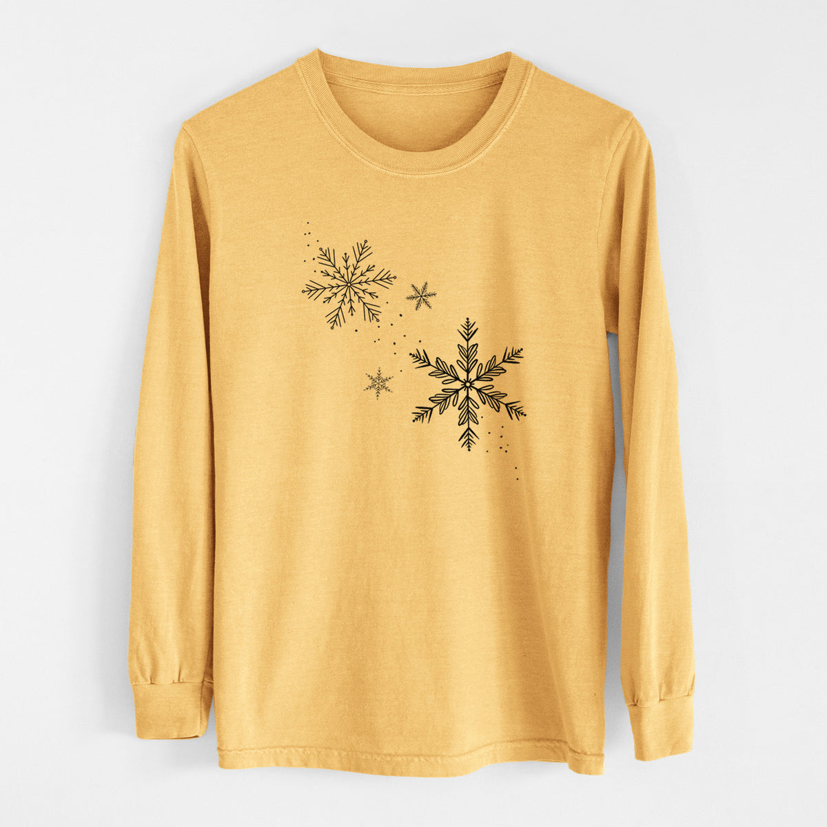 Golden wheat yellow Comfort Colors long sleeve shirt laid flat, printed with delicate snowflakes of different sizes falling.