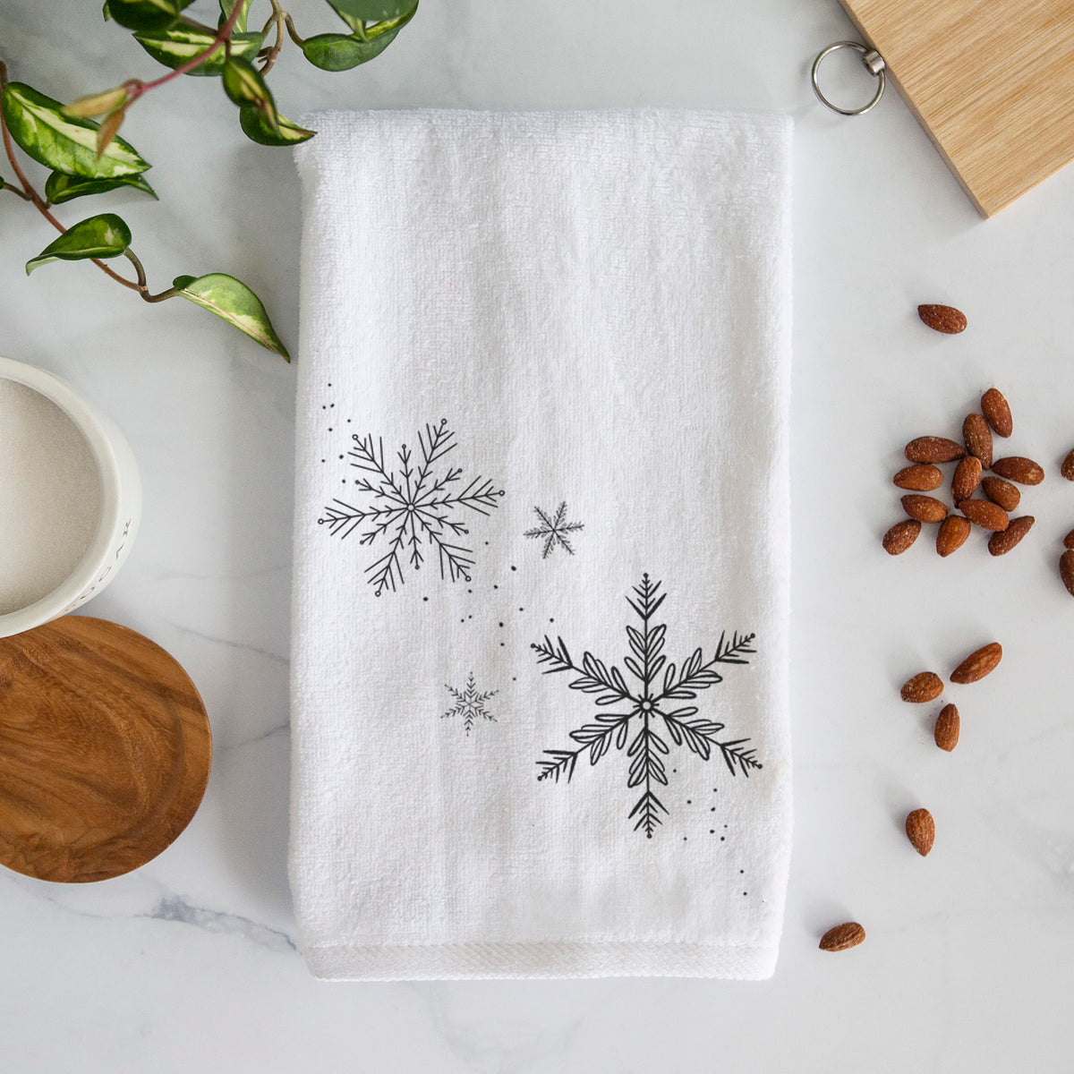 White hand towel printed with delicate snowflakes of different sizes falling.