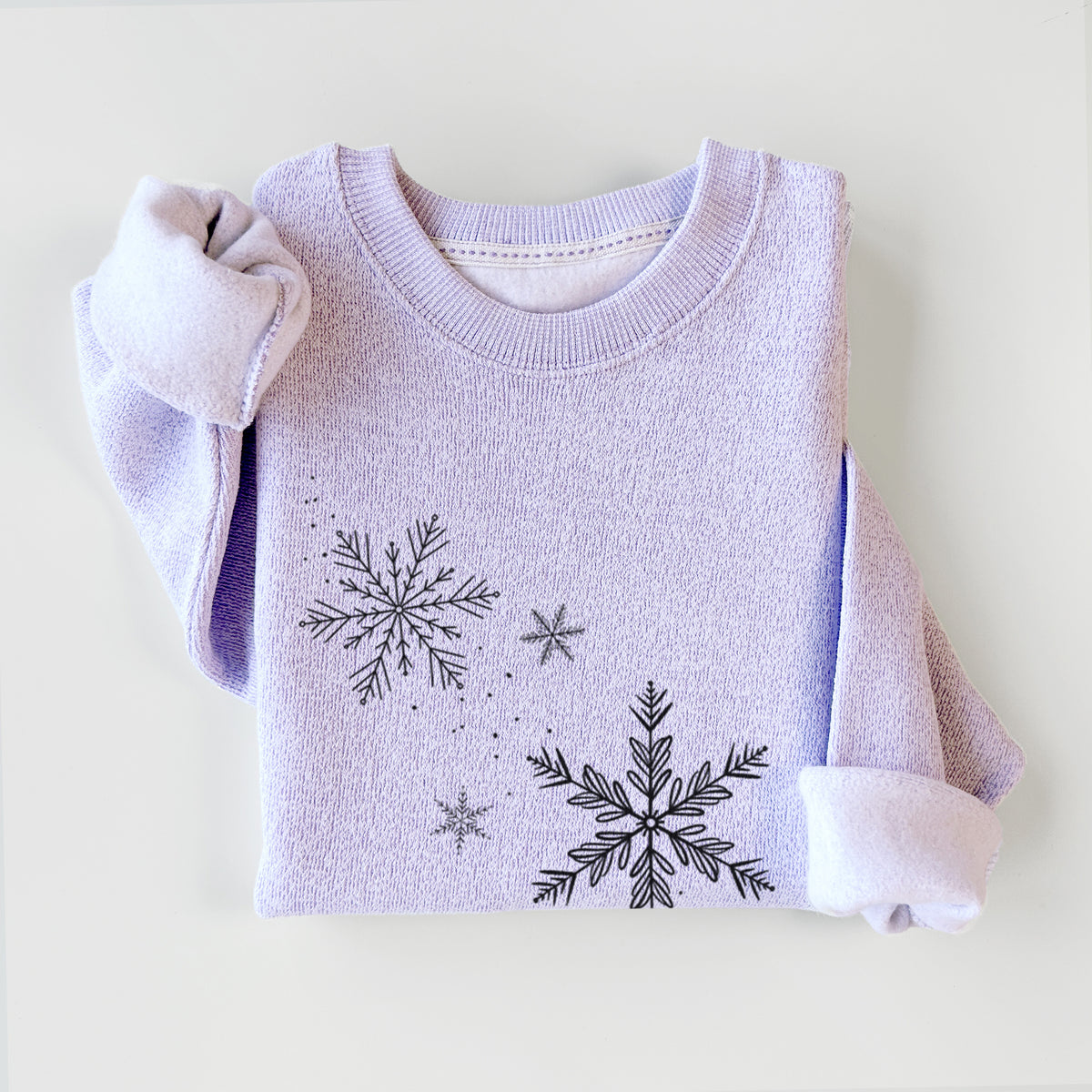 Ice purple knit sweatshirt printed with delicate snowflakes of different sizes falling, styled flat.