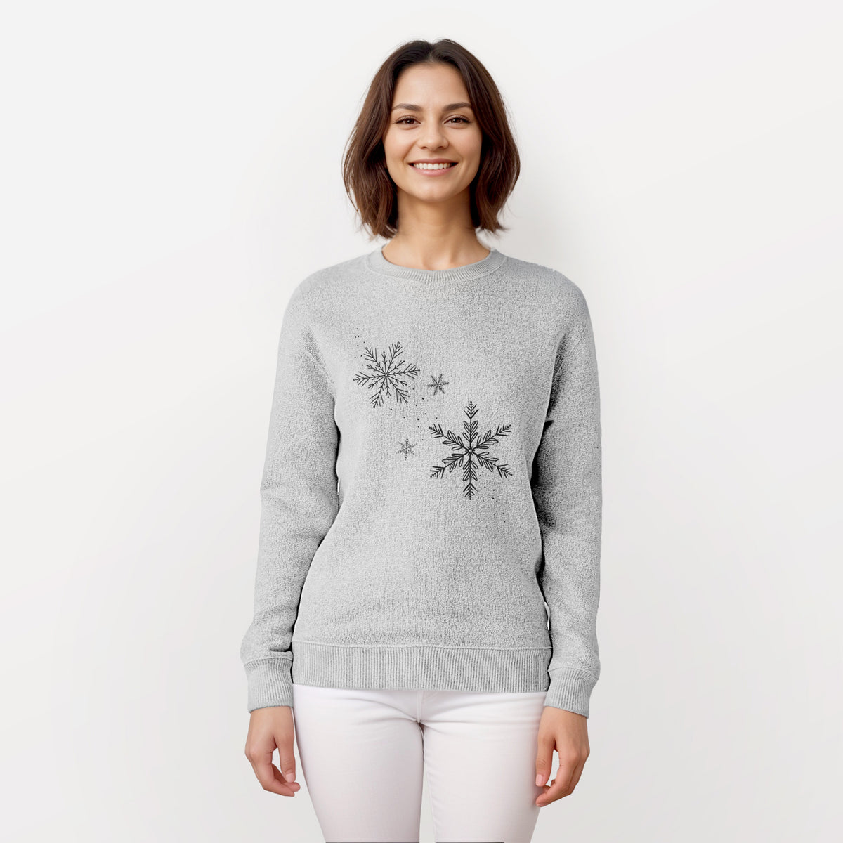 Woman wearing a knit sweatshirt printed with delicate snowflakes of different sizes falling.