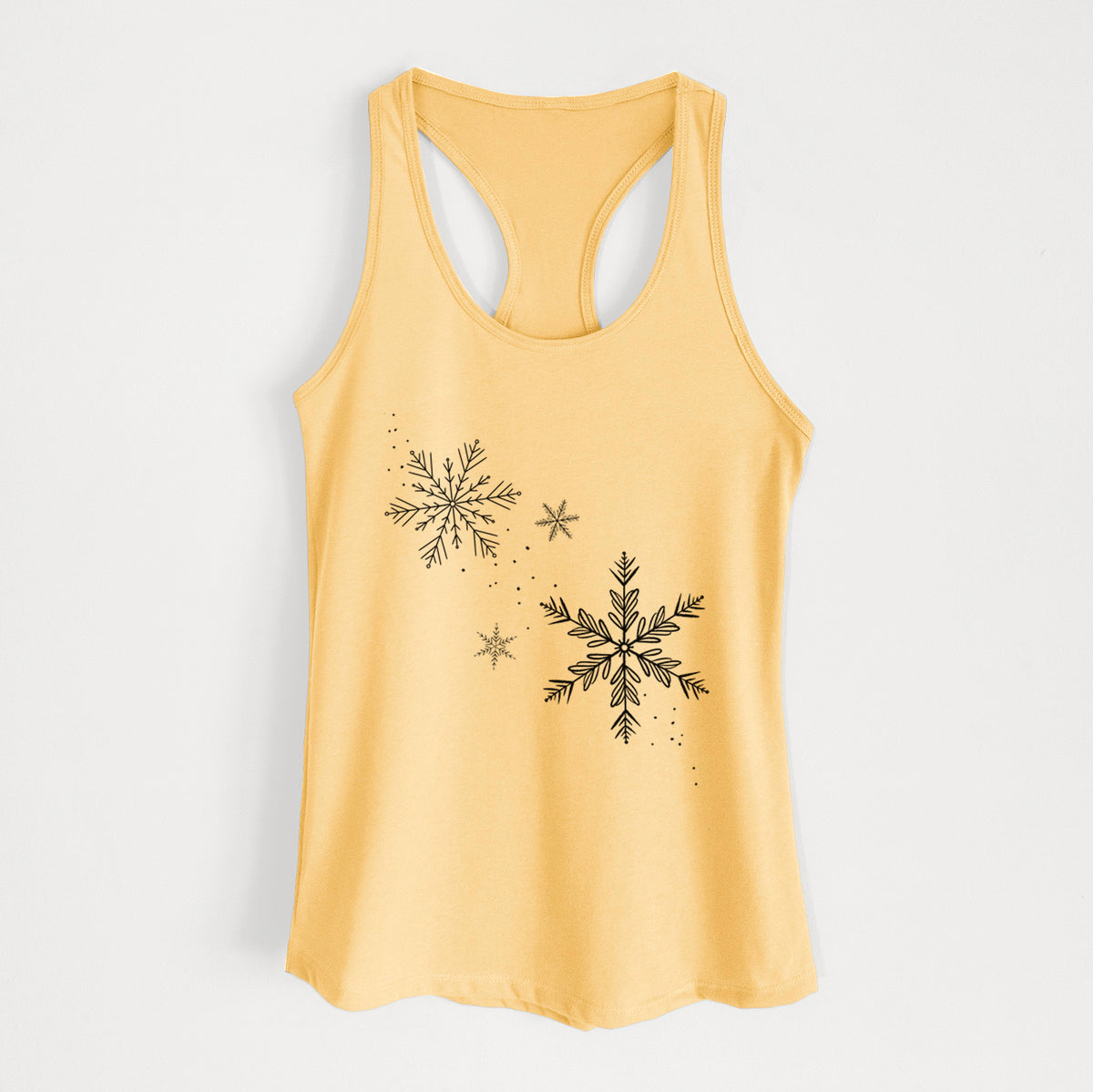 Banana cream women's racerback tank top laid flat, printed with delicate snowflakes of different sizes falling.